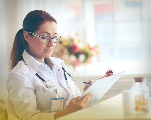 Женщина-врач пишет на планшетке.